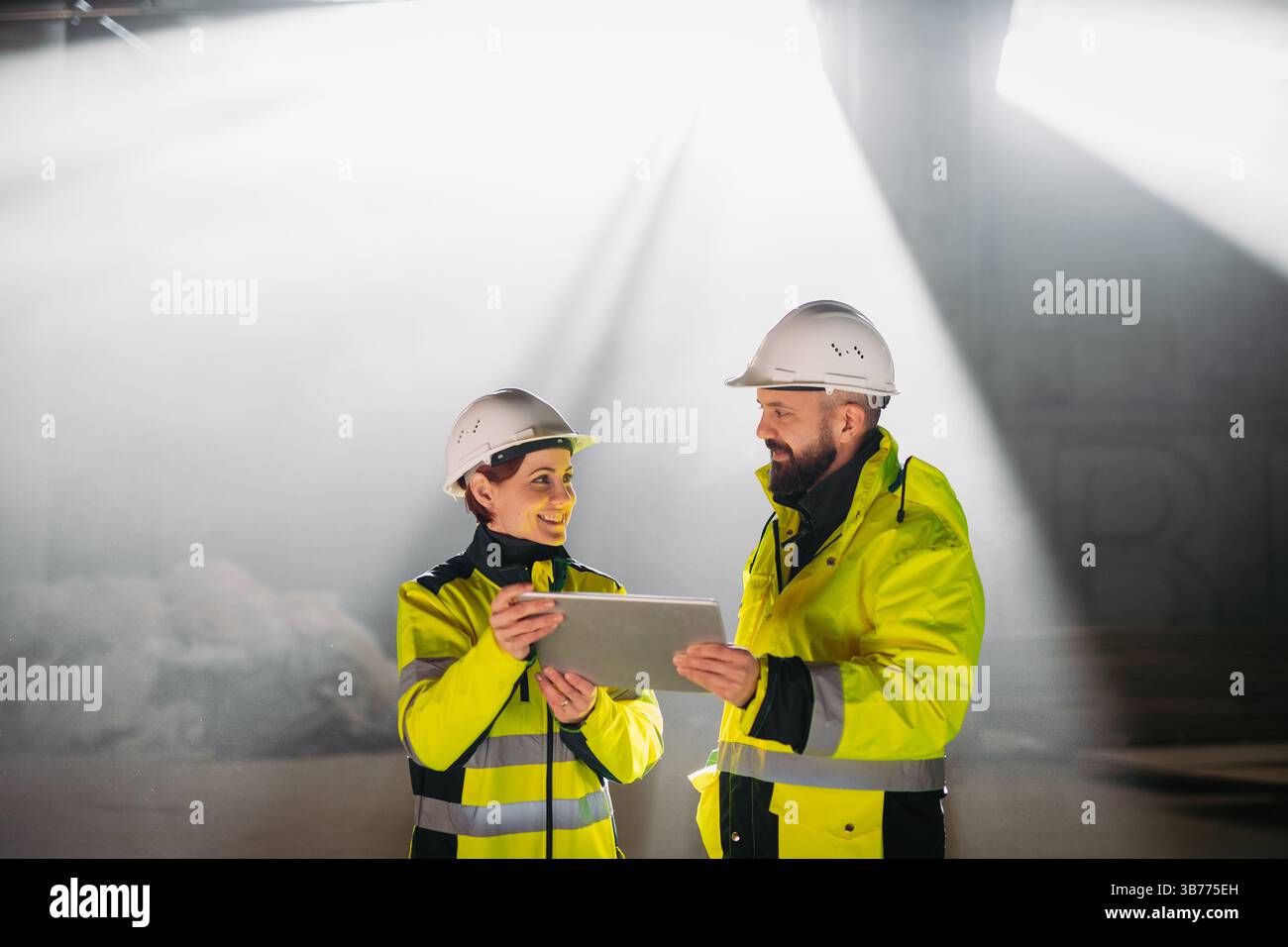Engineers discussing construction plans using a tablet on site. Stock Photo