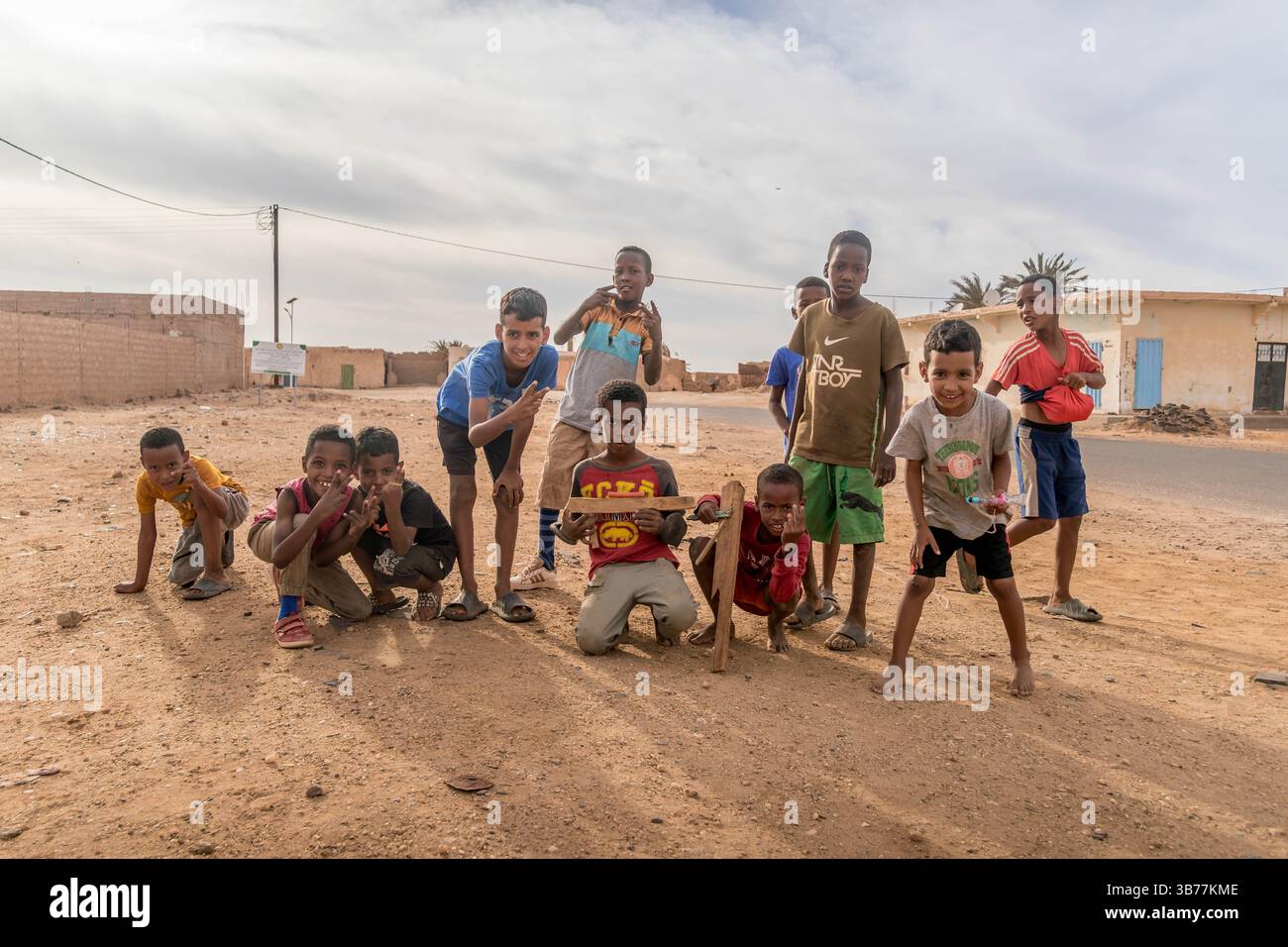 A group of African children playfully poses in a dusty rural setting ...