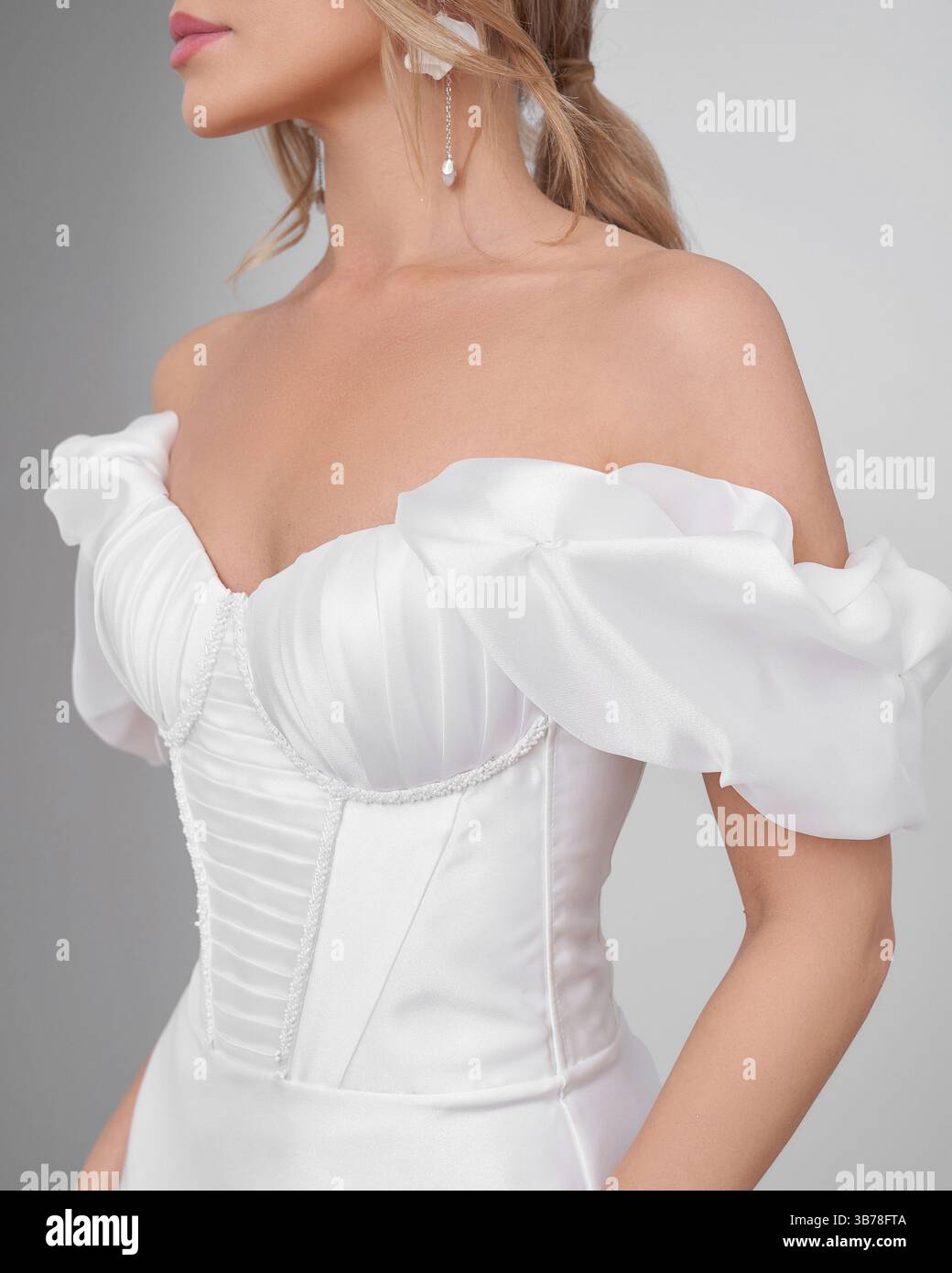 Blonde woman in elegant wedding dress poses gracefully in bright interior setting Stock Photo