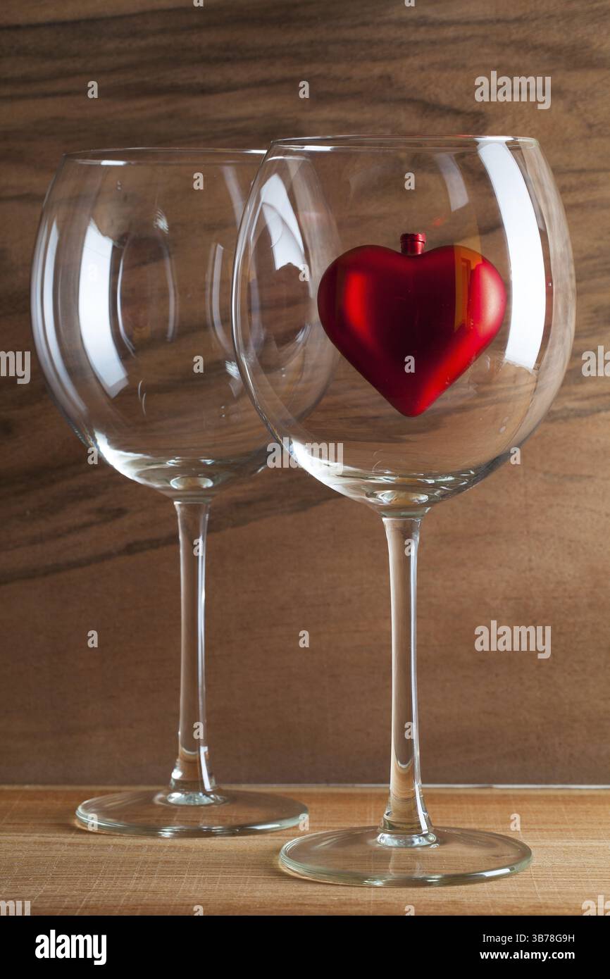 Two glasses of wine and red heart on the wooden background from real wood veneer with interesting growth Stock Photo