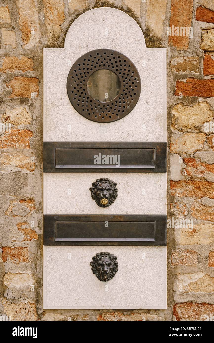 Close-ups of building facades in Venice, Italy. An old vintage intercom and a mailbox on a stone wall. On door where placed this old rusty doorbells Stock Photo