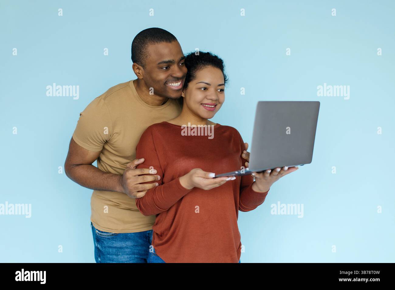 Young african american couple using laptop on blue background in studio Stock Photo