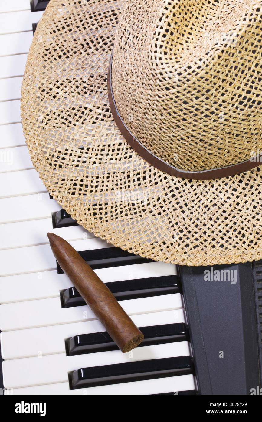 Detail of piano keyboard, straw hat and luxury cigar Stock Photo - Alamy