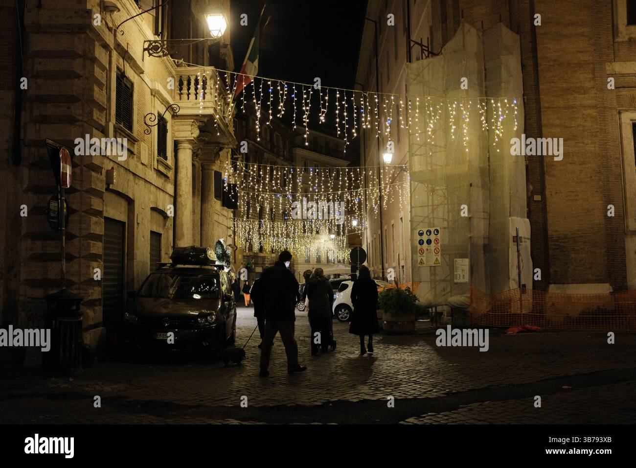 Narrow Roman streets decorated with Christmas lights at night people walking and festive atmosphere in old town Italy. High quality photo Stock Photo