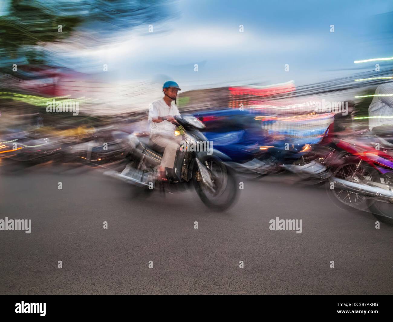 Motorcycles riding along a busy city road at twilight, blurred lights ...