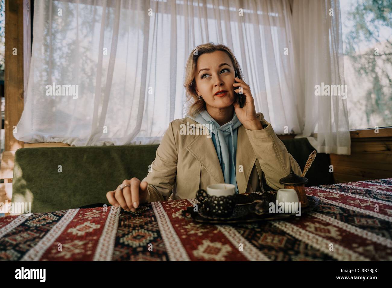 Woman on a Phone Call in a Cozy Cafe Setting Stock Photo