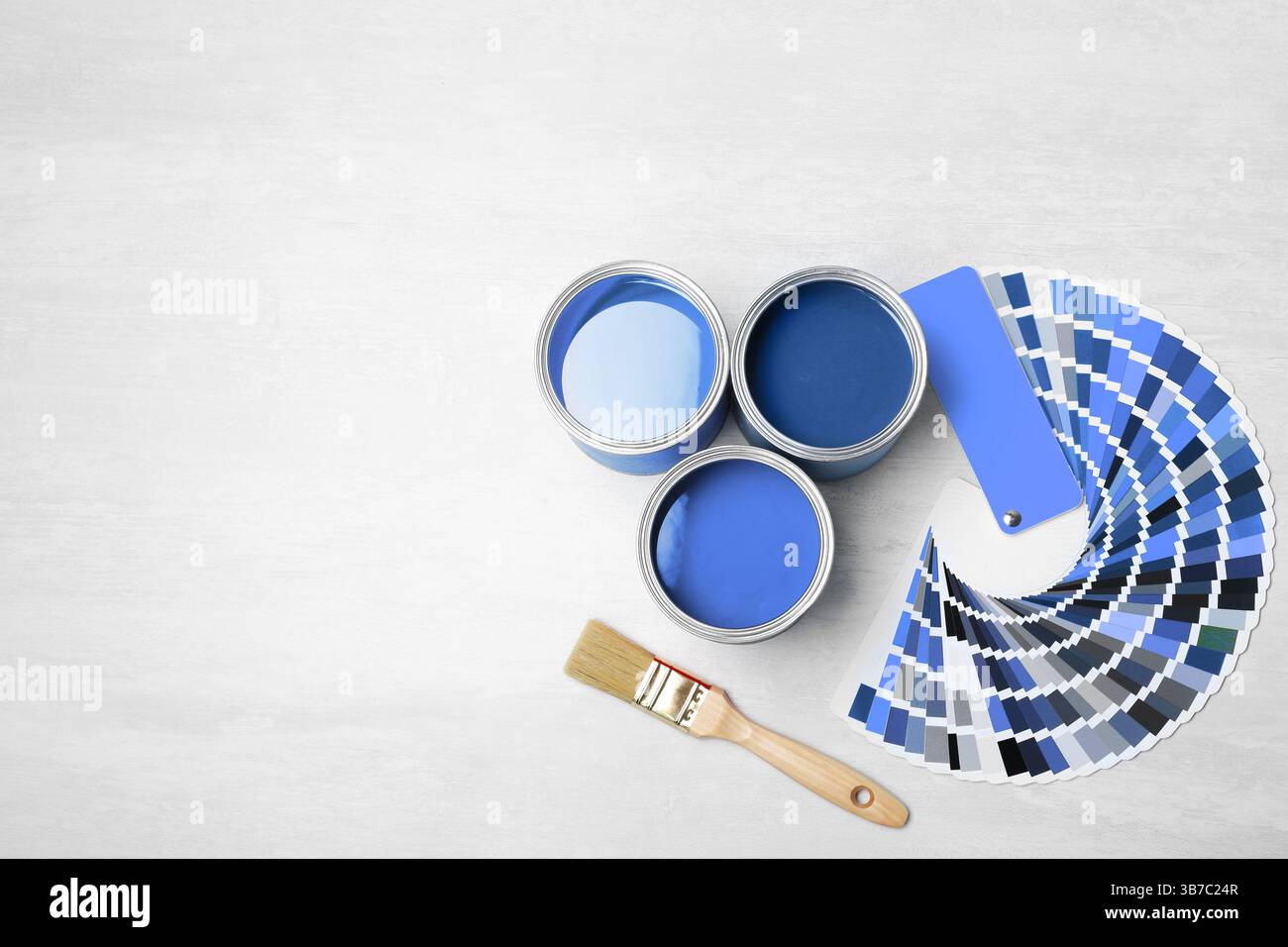 Cans with paint in shades of blue, brush and color palette on white ...