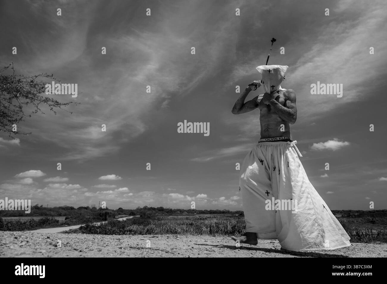 An Afro-Colombian man walks barefoot while whipping himself as part of a penance ritual during the Holy Week procession in Santo Tomás, Colombia. Stock Photo