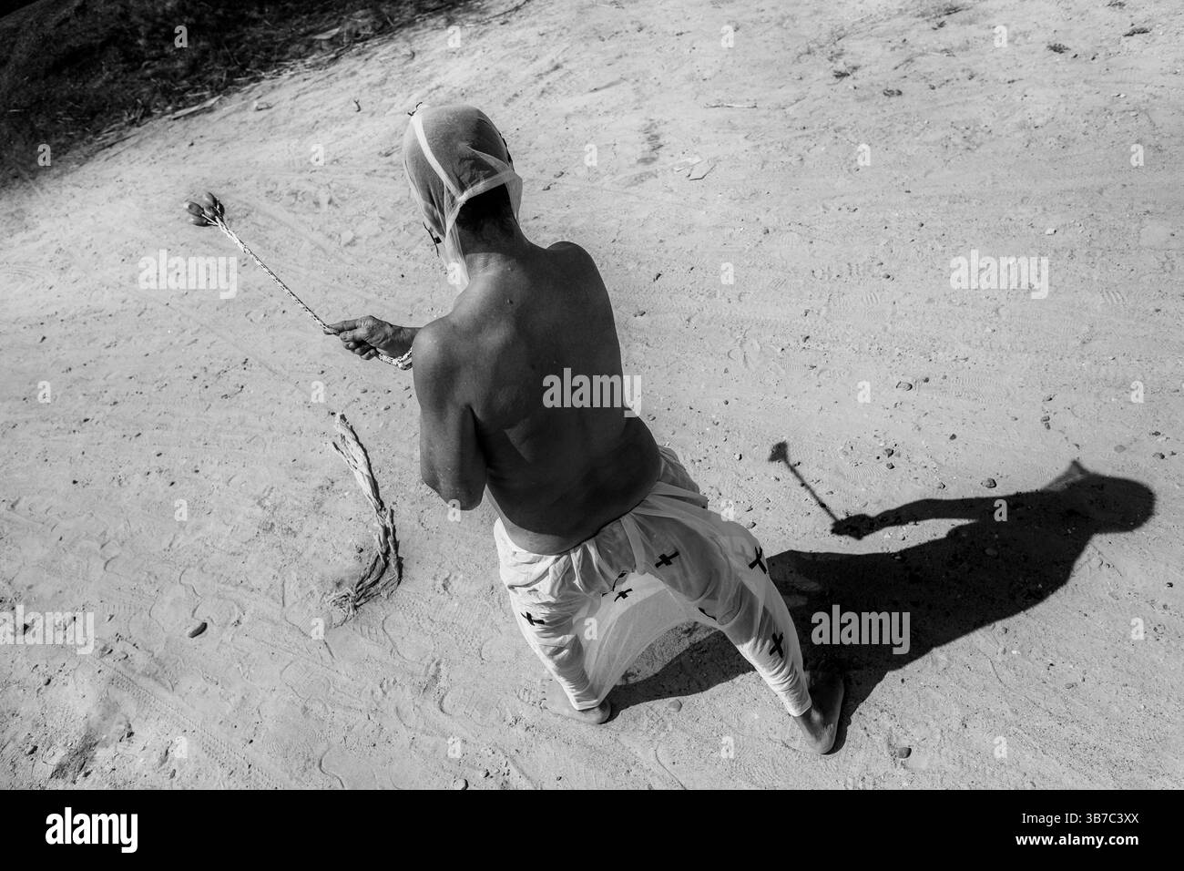 An Afro-Colombian man walks while whipping himself as part of a penance ritual during the Holy Week procession in Santo Tomás, Colombia. Stock Photo