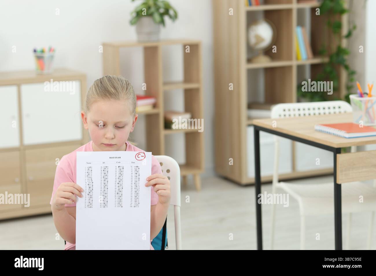School grade. Sad girl holding answer sheet with letter C and minus ...