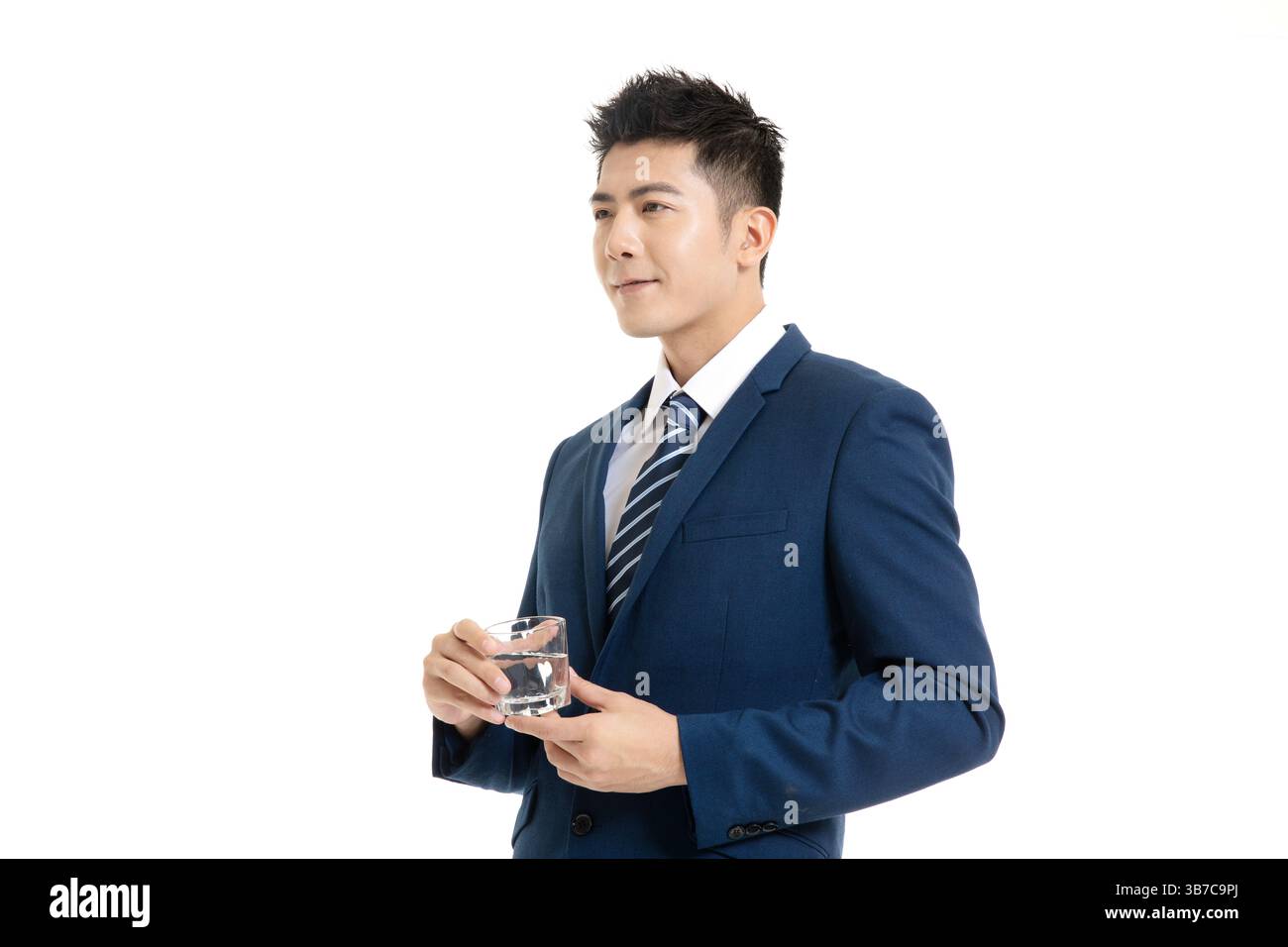 A sharp-dressed professional in an office setting, holding a glass during a casual networking event. Stock Photo