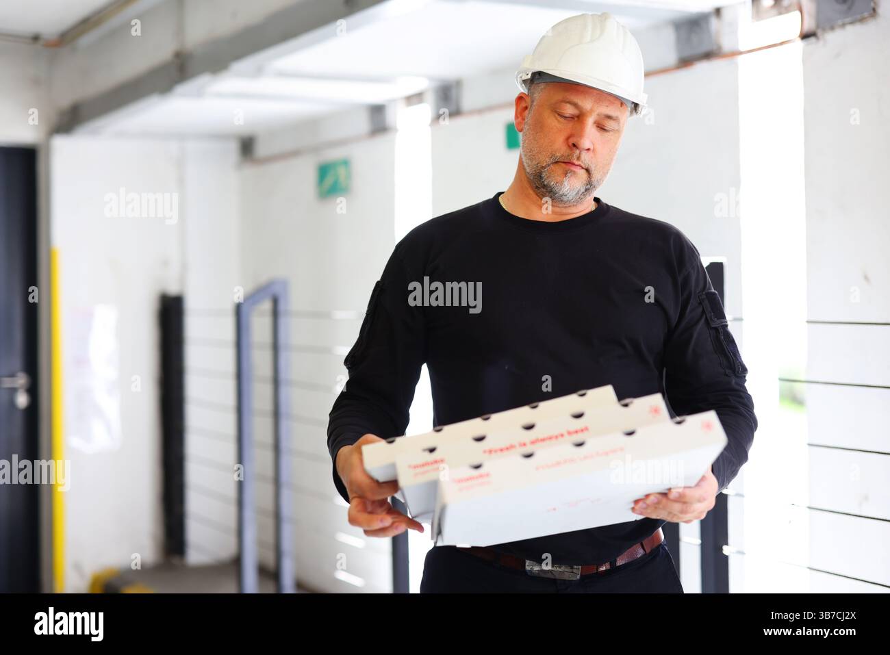 Worksite Break Construction worker in hard hat holding pizza boxes, taking a break at ...