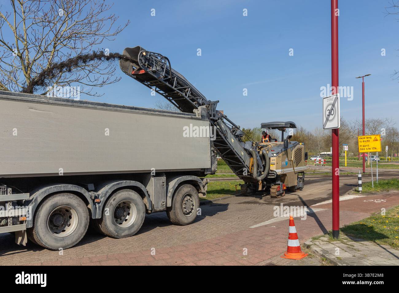 Road Loading A milling machine removes asphalt from a road, loading it into a truck ...