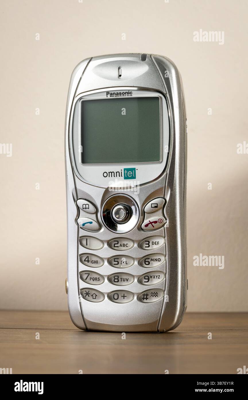 Old silver vintage Panasonic GD75 mobile phone standing on a wooden table, representing past communication technology Stock Photo
