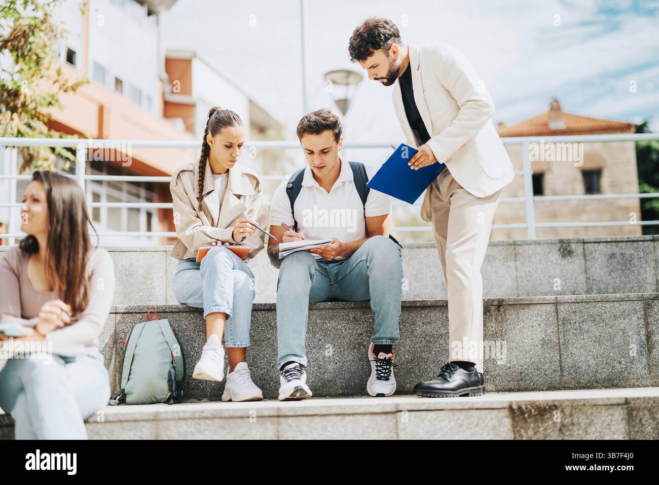High school students collaborating with professor's guidance outdoors Stock Photo