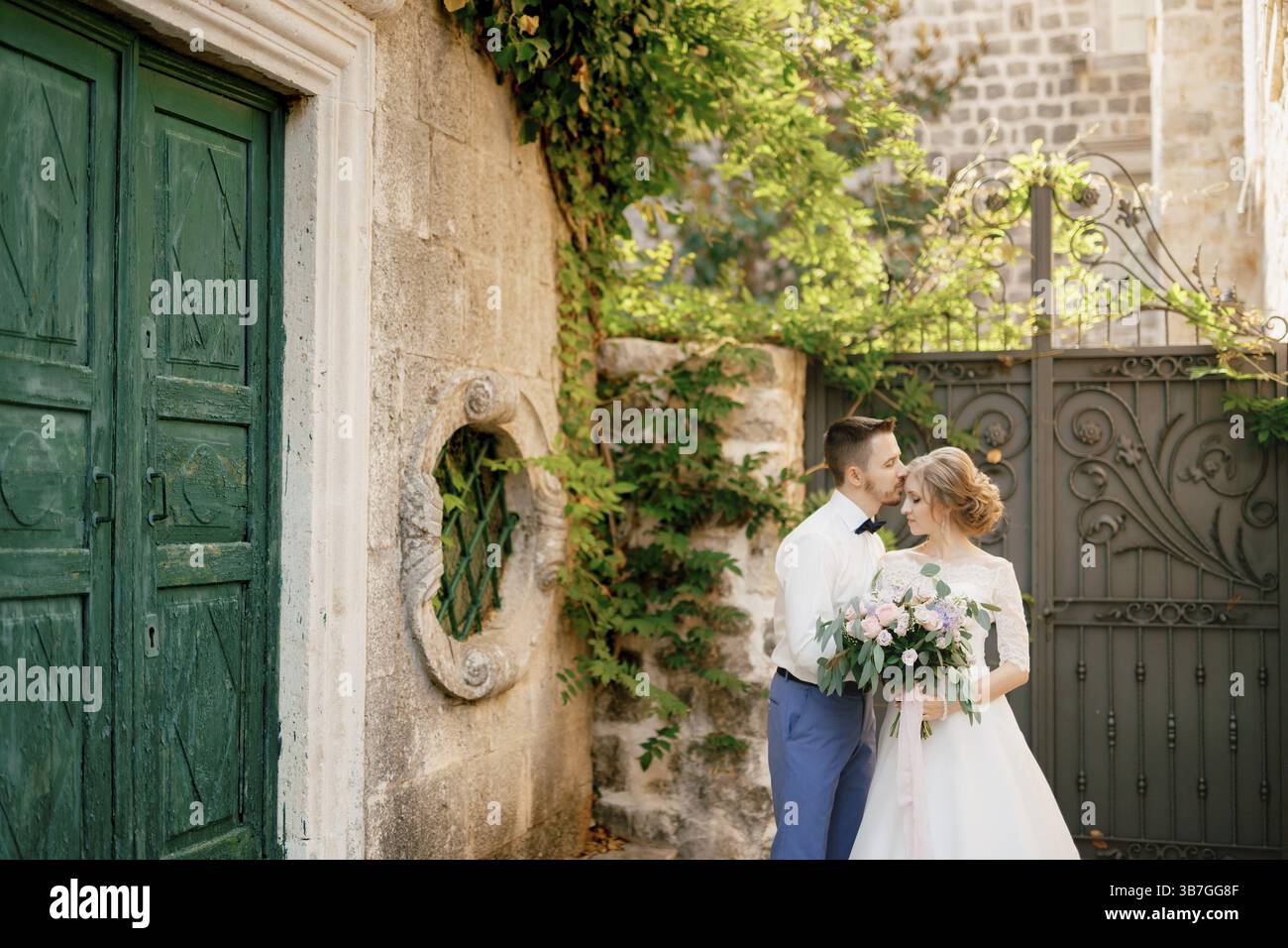 The bride and groom stand hugging near beautiful old green door, the ...