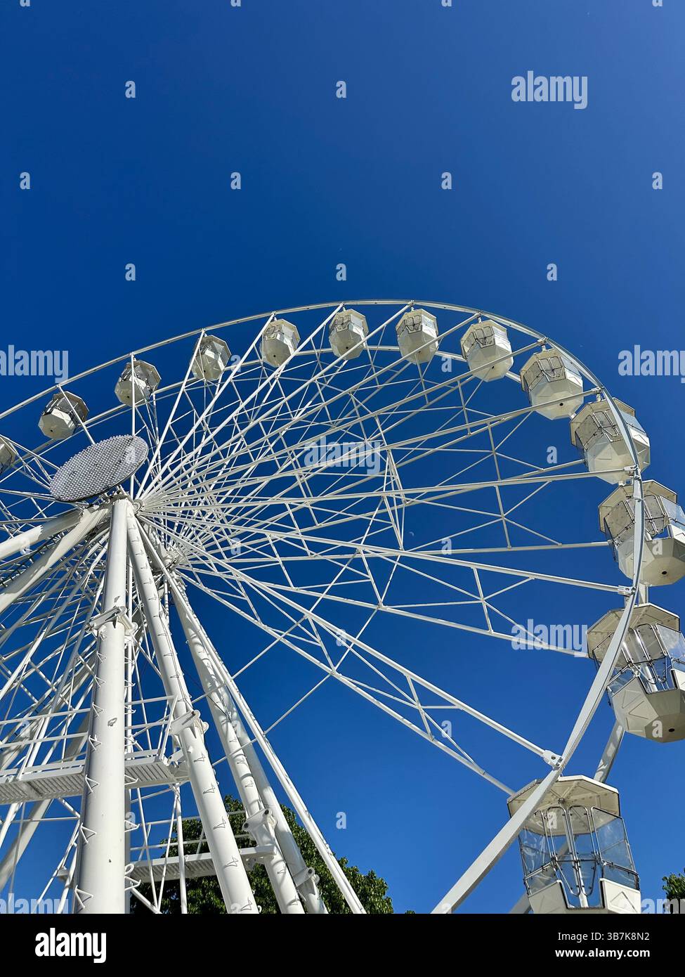 Low angle view of a white Ferris wheel against a clear blue sky in Grosvenor Park, Chester. - Smartphone Captured Stock Image