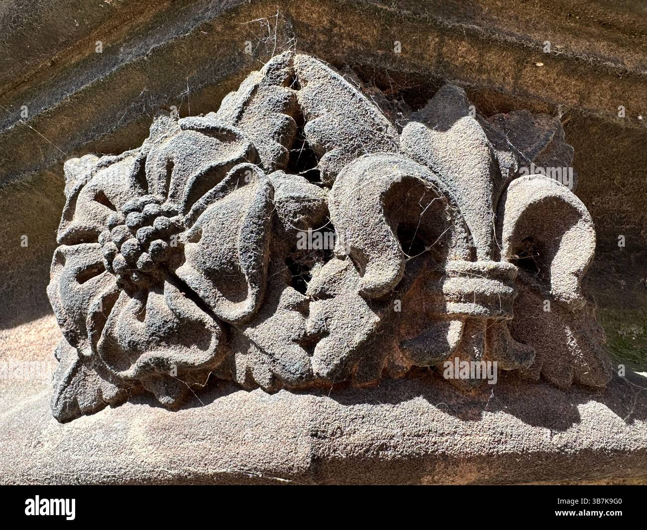 Close up of ornate red brick carvings on Chester Cathedral featuring a rose and fleur-de-lis with visible cobwebs - Smartphone Captured Stock Image Close up of ornate red brick carvings on Chester Cathedral featuring a rose and fleur-de-lis with visible cobwebs - Smartphone Captured Stock Image