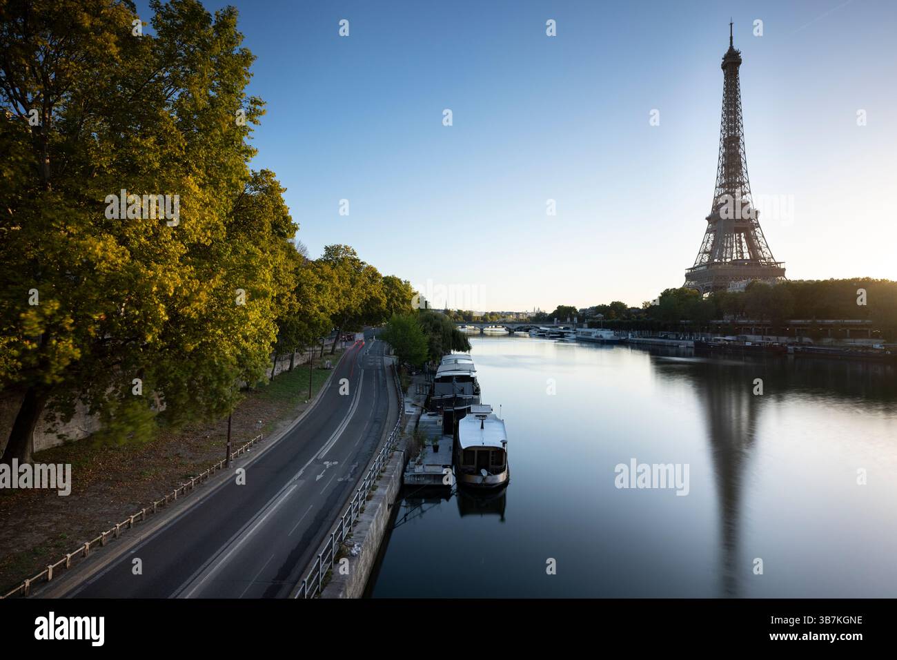 View of the Eiffel Tower with soft sunlight on the Seine River, also visible is the Via Georges Pompidou in Paris, France. A tranquil urban scene show Stock Photo