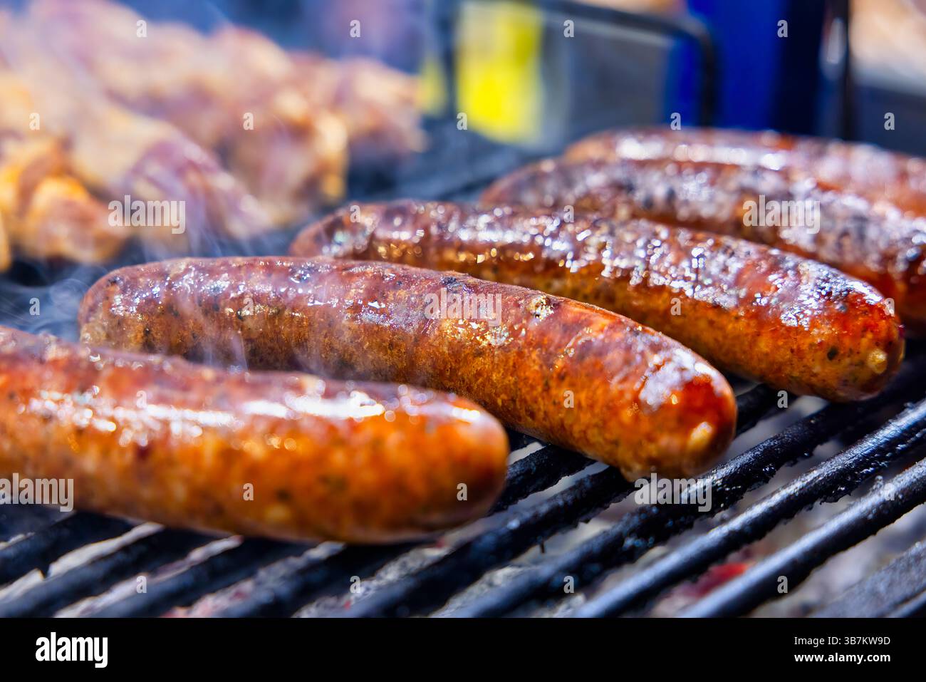 Juicy sausages sizzling on the grill, with a golden, crispy skin and smoky aroma filling the air—grill perfection in every bite. Stock Photo