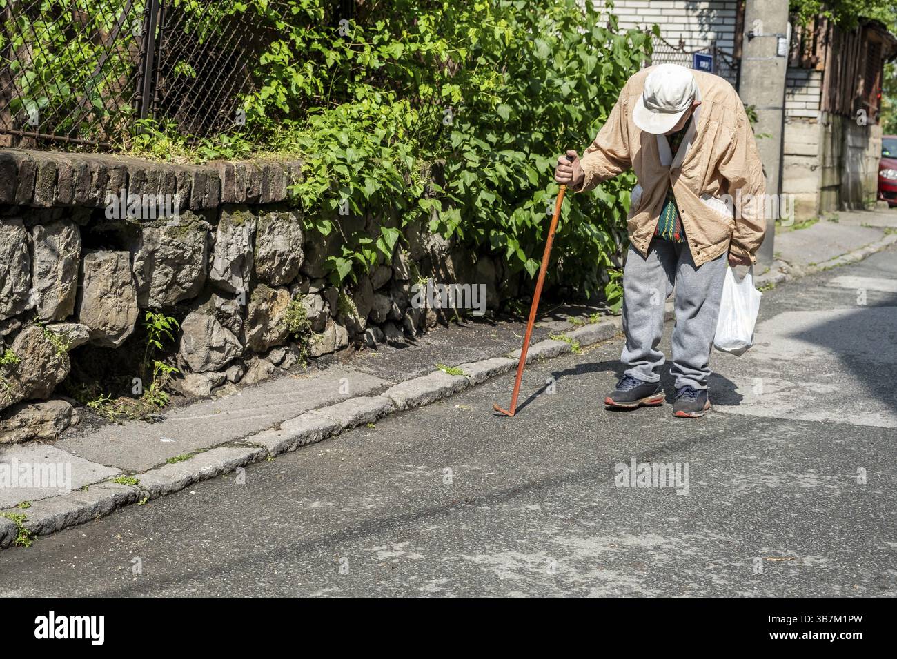 Elderly man with cane walks bent down a sunny street Stock Photo - Alamy