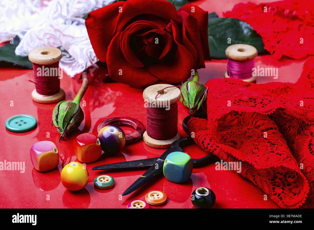 Thread, bead, button, and rose on bright red background Stock Photo - Alamy