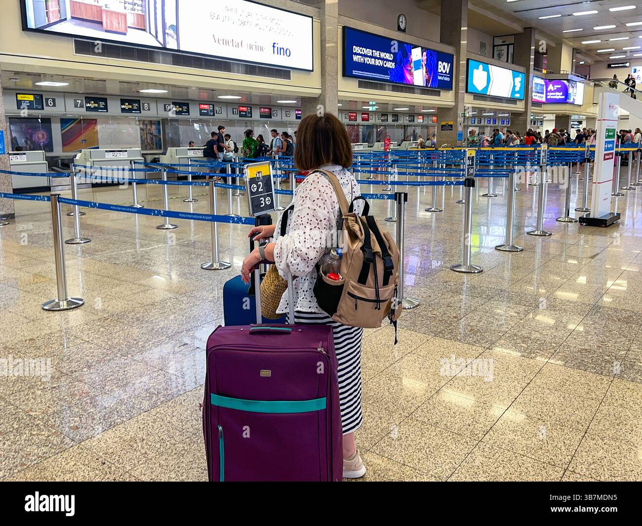 Luqa, Malta - 9 August 2023: Person with luggage looking for the check-in desk for her flight at Malta International Airport at Luqa. - Smartphone Captured Stock Image