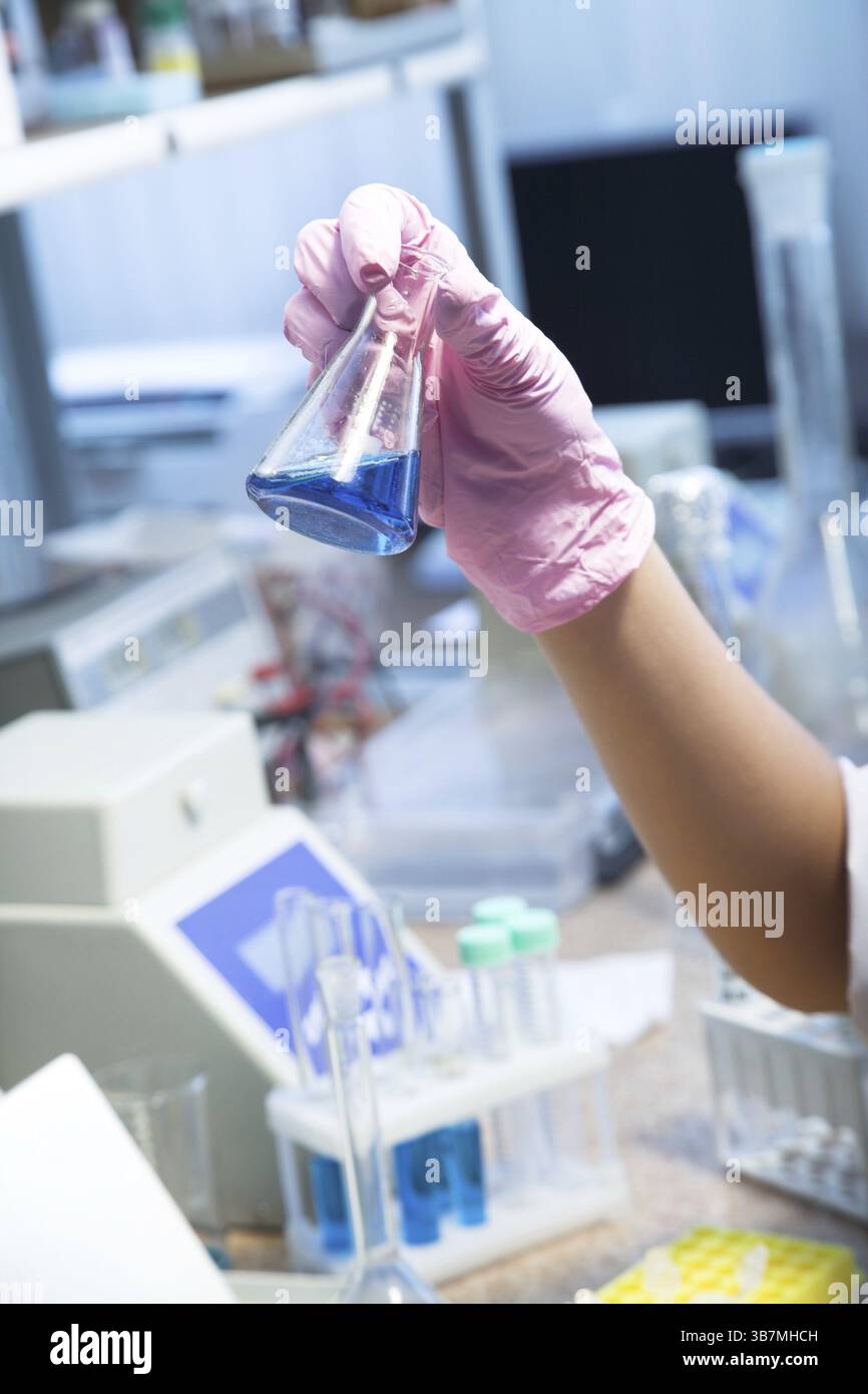 Female researcher look at retort with blue liquid Stock Photo - Alamy