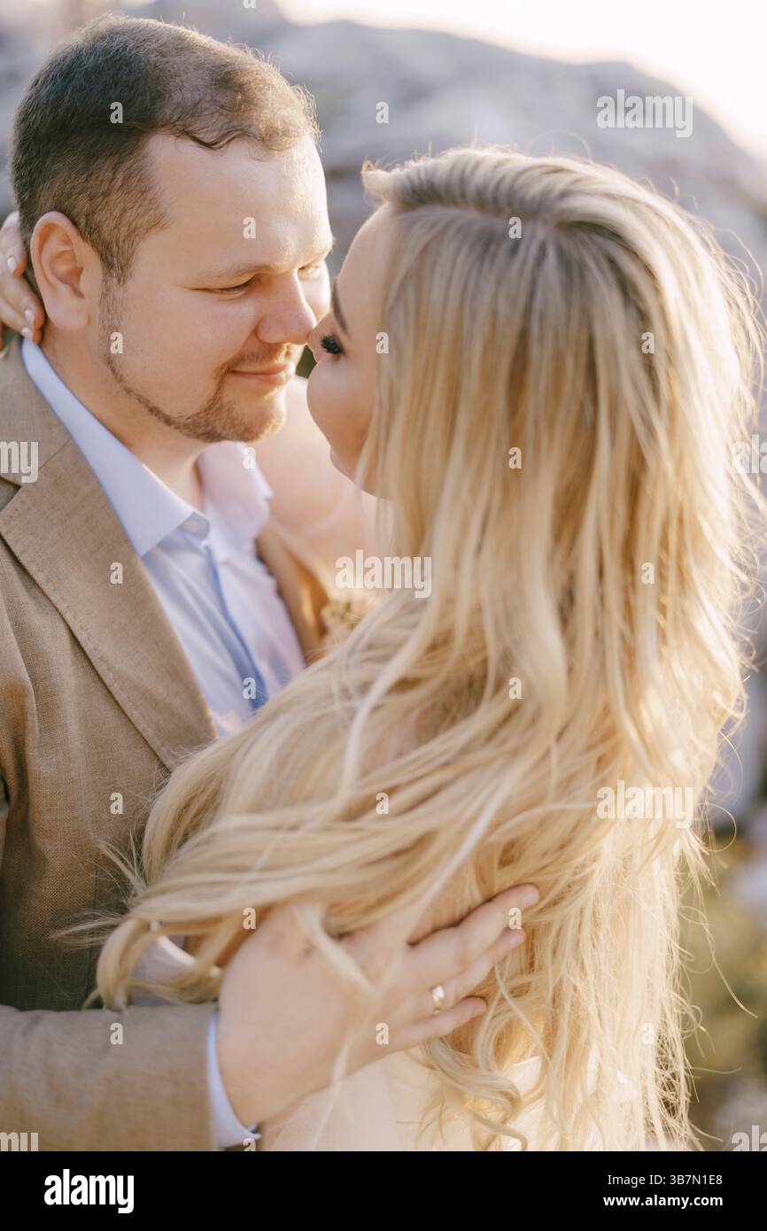Groom hugs bride in a white dress. Close-up. Stock Photo
