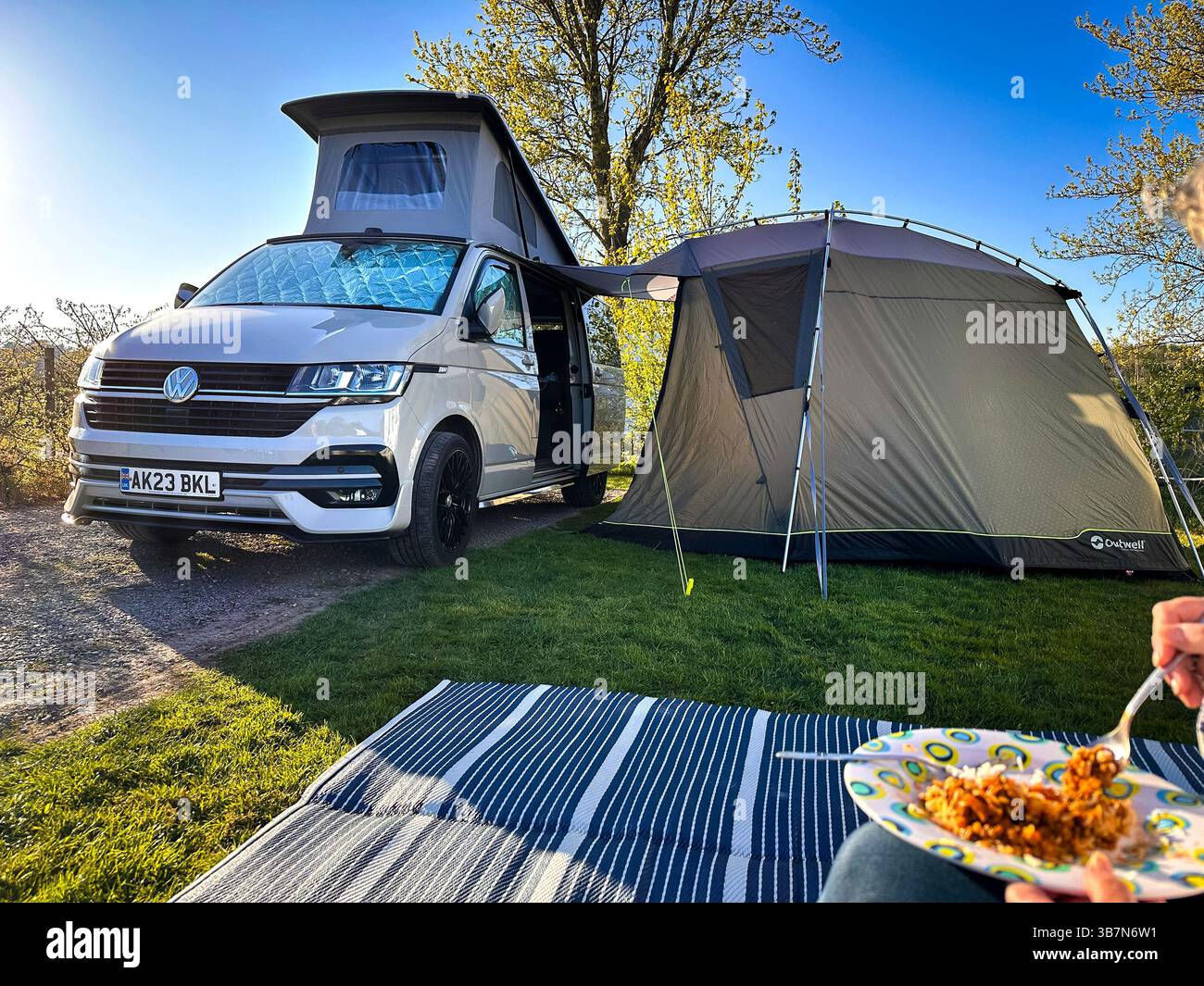 camping holiday eating meal in front of ascot grey volkswagen T6 campervan with attached awning tent - Smartphone Captured Stock Image