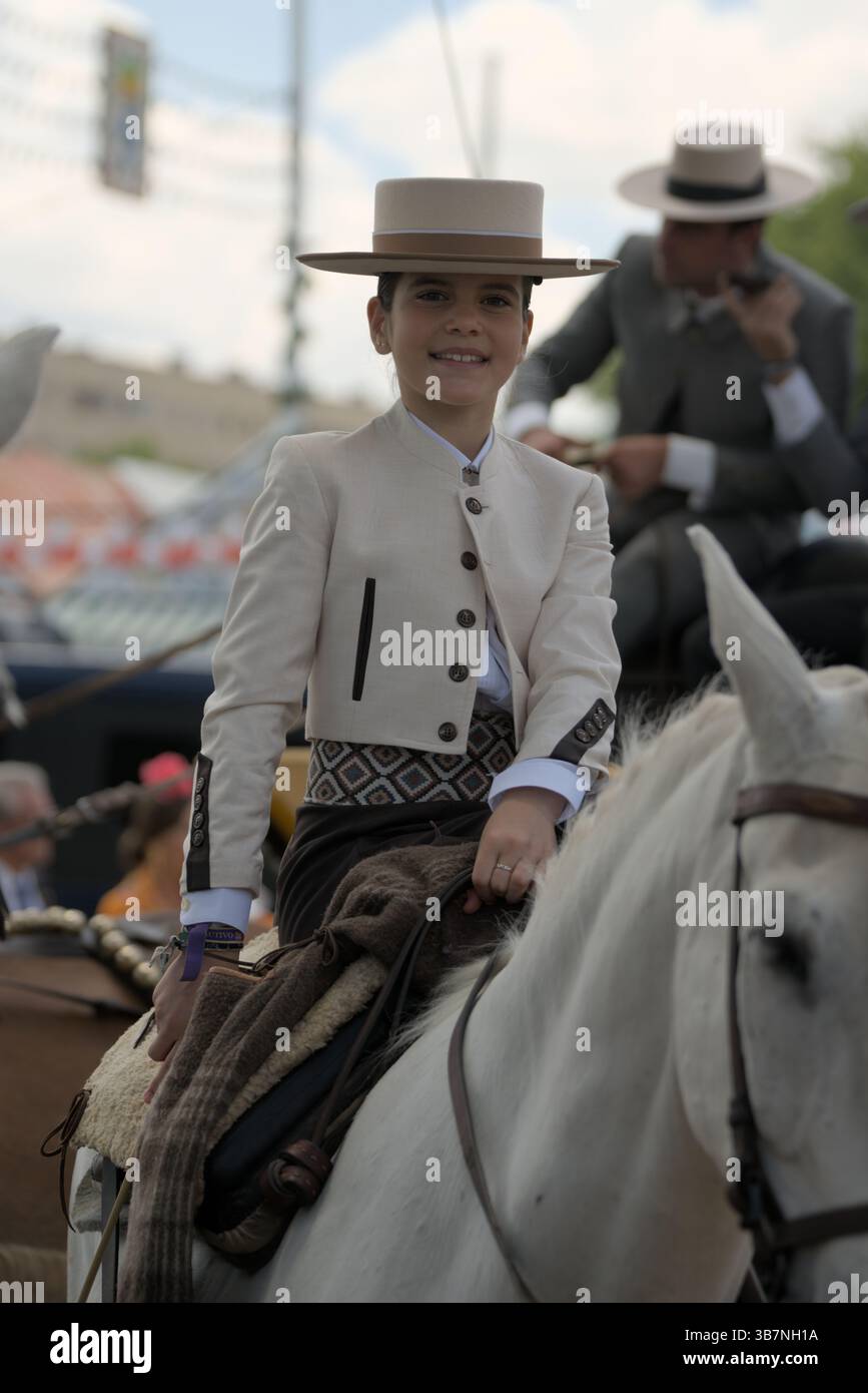 Smiling child rider in traditional outfit on a white horse during ...