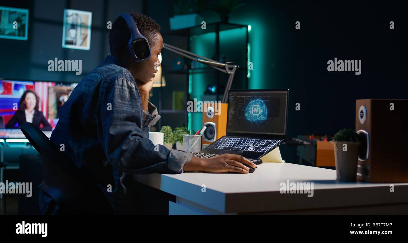 Programmer in living room office typing on keyboard, updating artificial intelligence neural networks, writing binary code scripts. Freelancing system administrator upgrading high tech AI, camera B Stock Photo