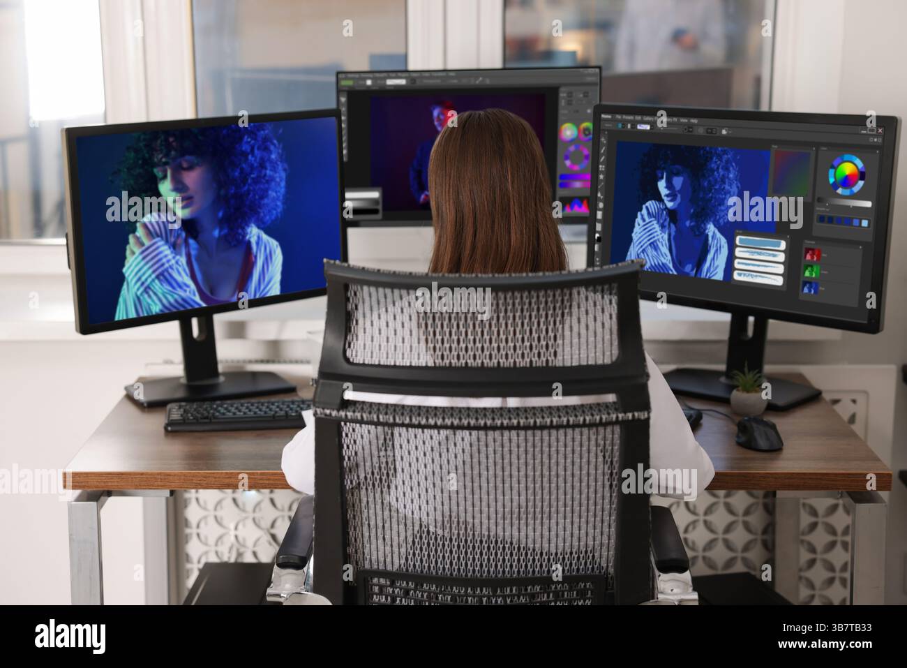 Designer working on different computers at table in office, back view Stock Photo