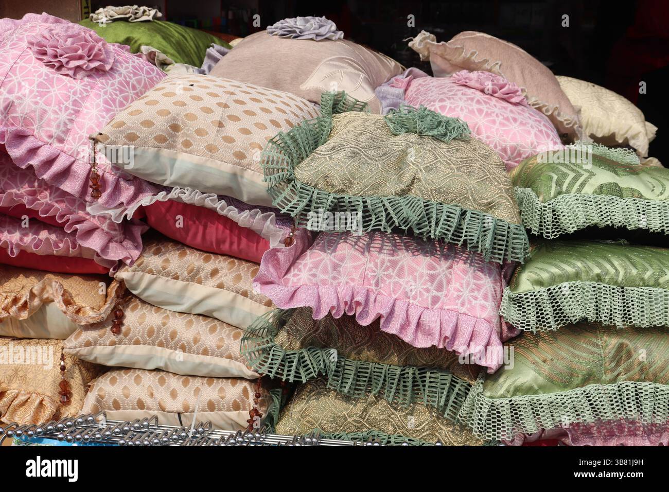 Display of many decorative pillows with various textures and colors; pink, gold, green, and beige colors. Each pillow has decorative ruffles and ornam Stock Photo