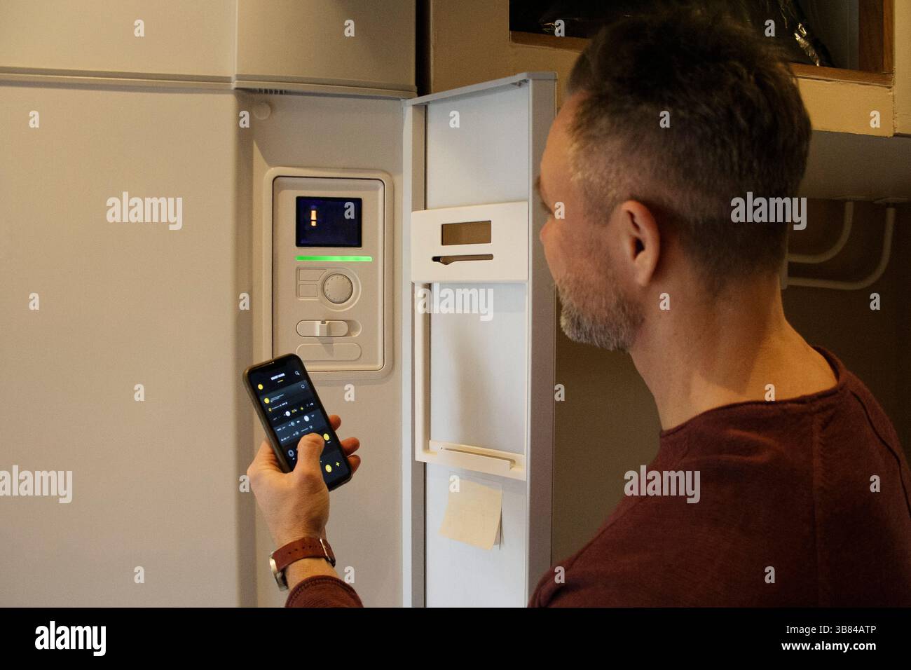 Man connecting smart phone with thermostat through app at home Stock Photo