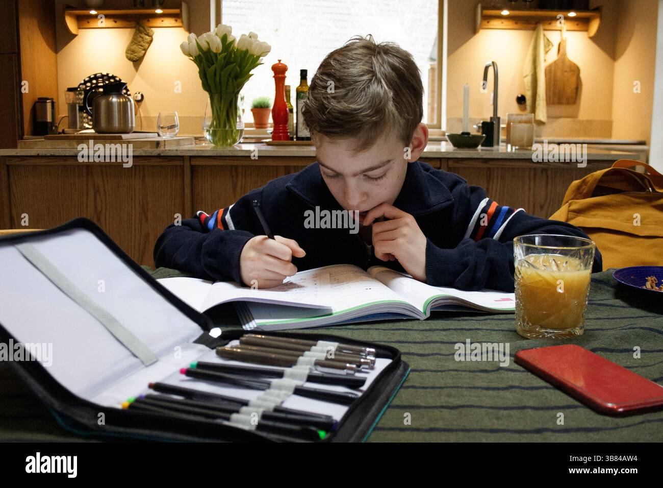 Thoughtful boy with set of colored pencils on table at home Stock Photo