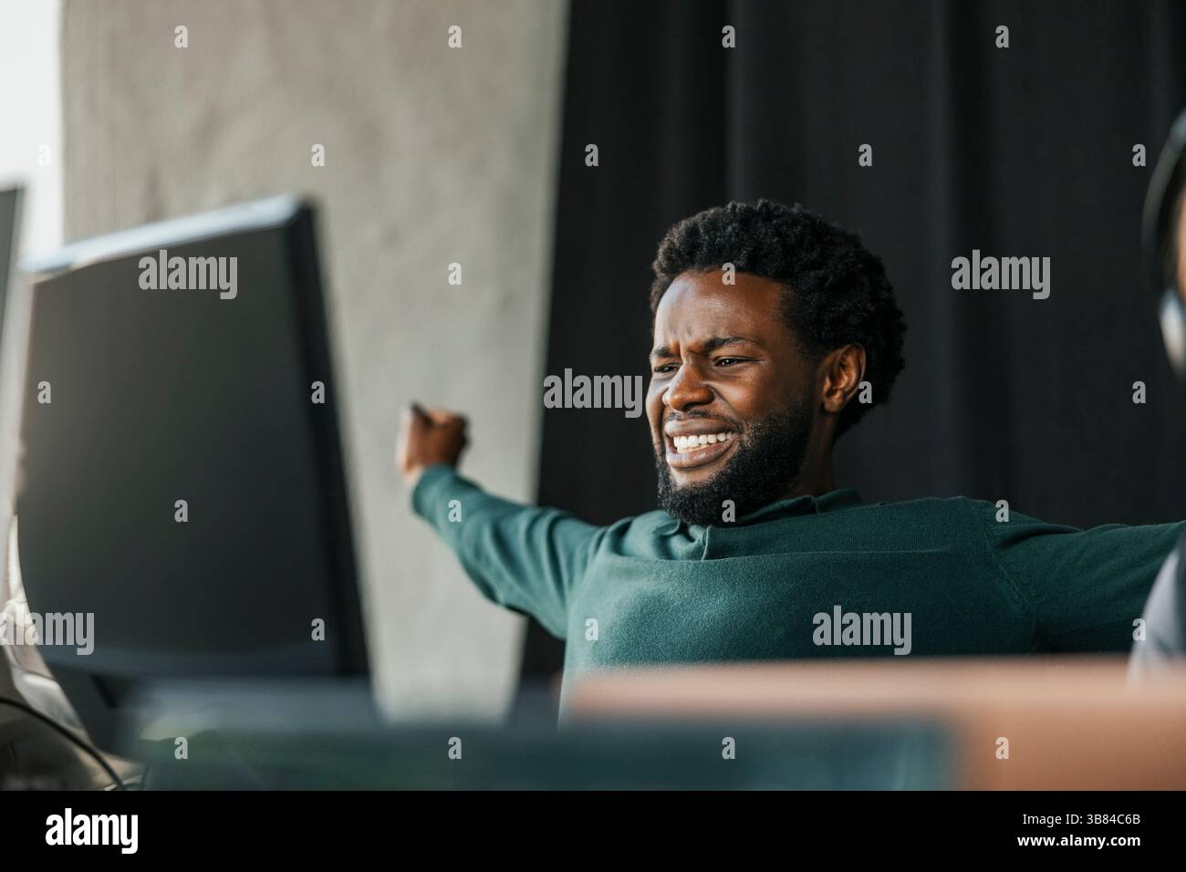 Male computer programmer stretching arms while sitting in tech hub Stock Photo