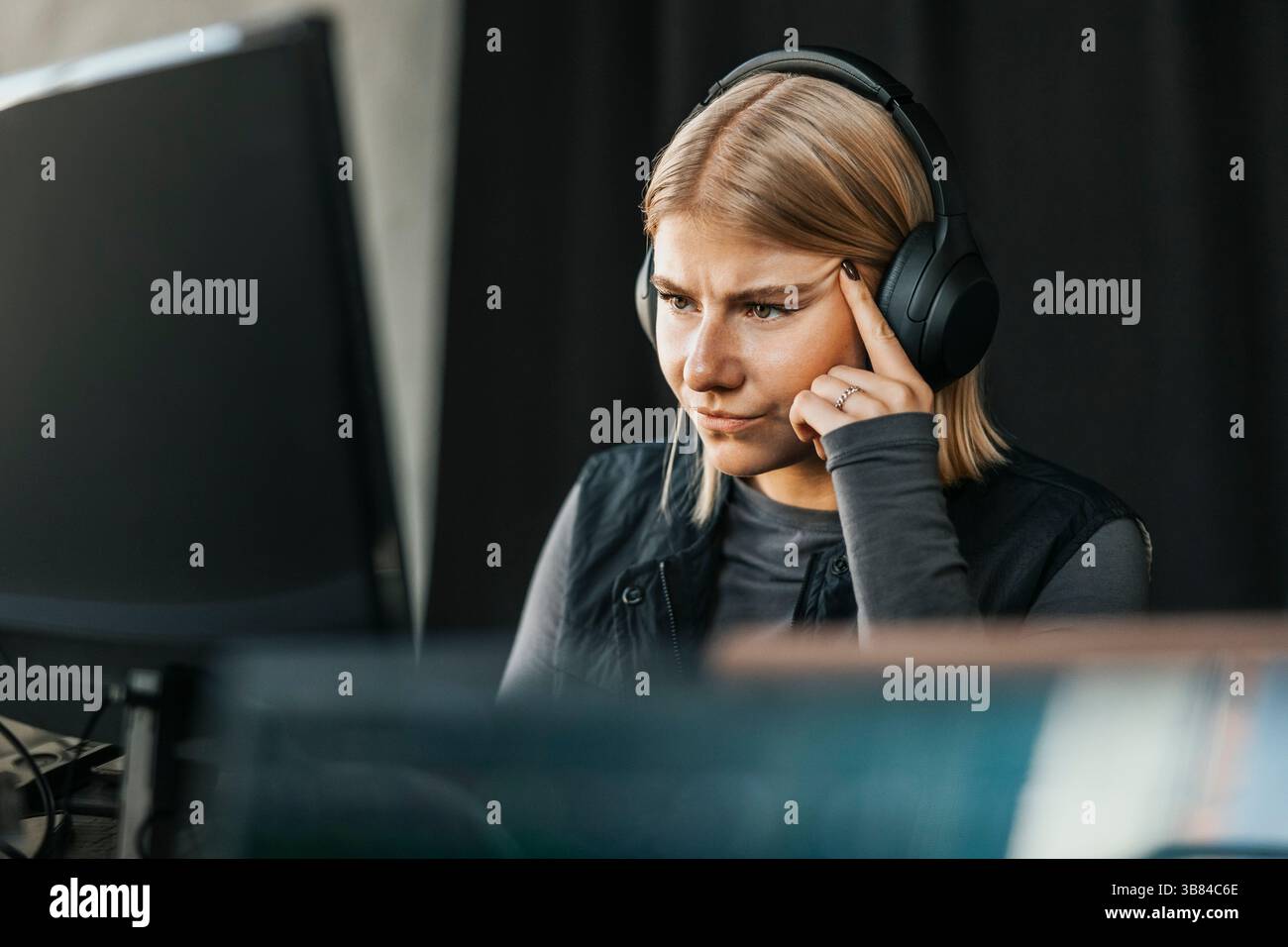 Concentrated female computer programmer wearing wireless headphones ...