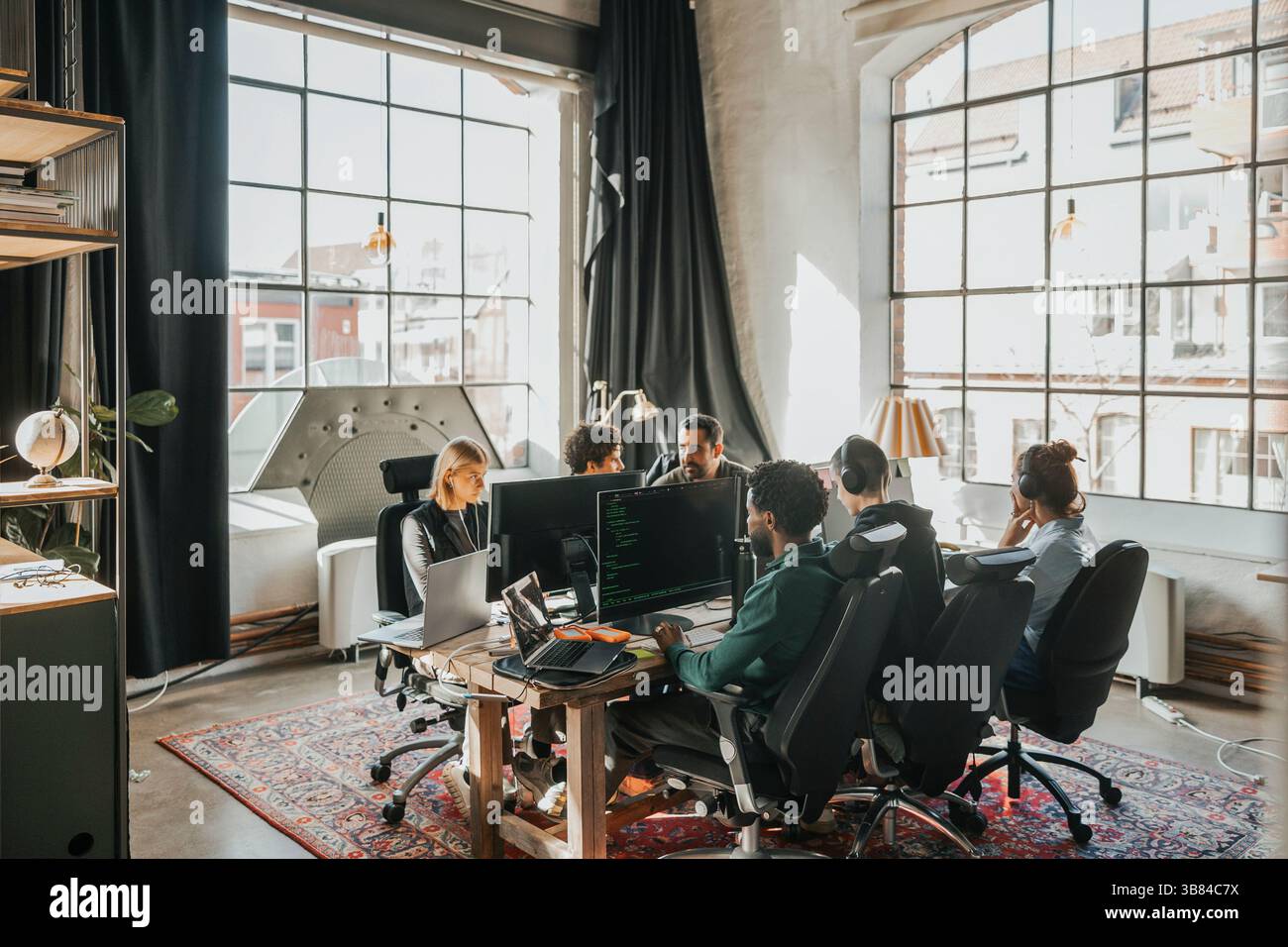 Group of multiracial software engineers working on desktop PC while sitting at desk in tech startup office Stock Photo
