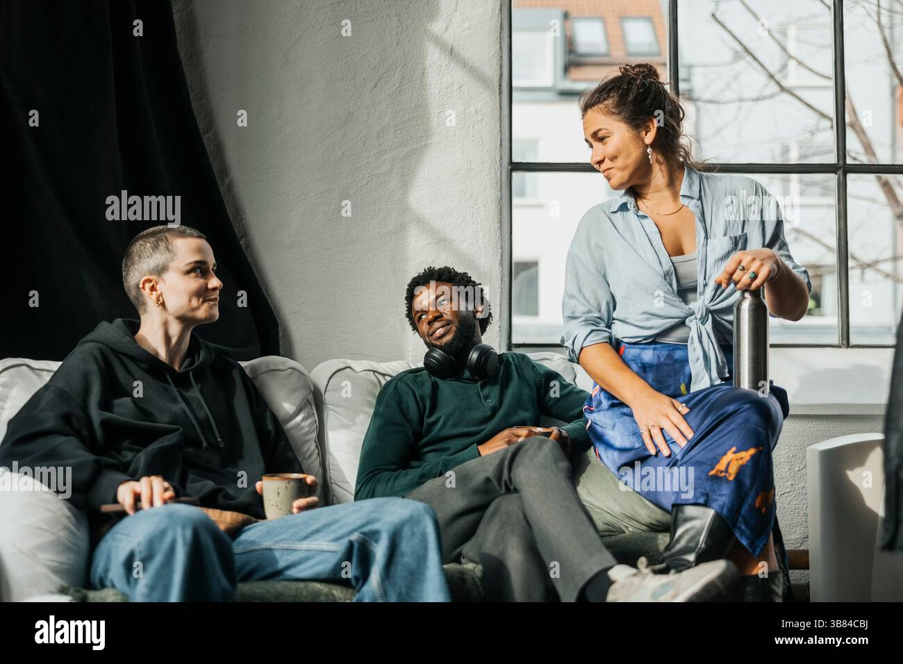 IT professionals talking with each other while sitting on sofa in tech hub Stock Photo