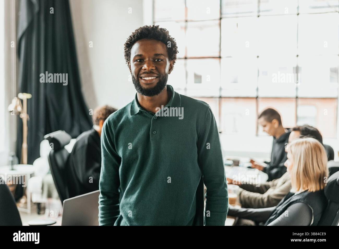 Portrait of smiling curly haired male computer programmer standing in office Stock Photo