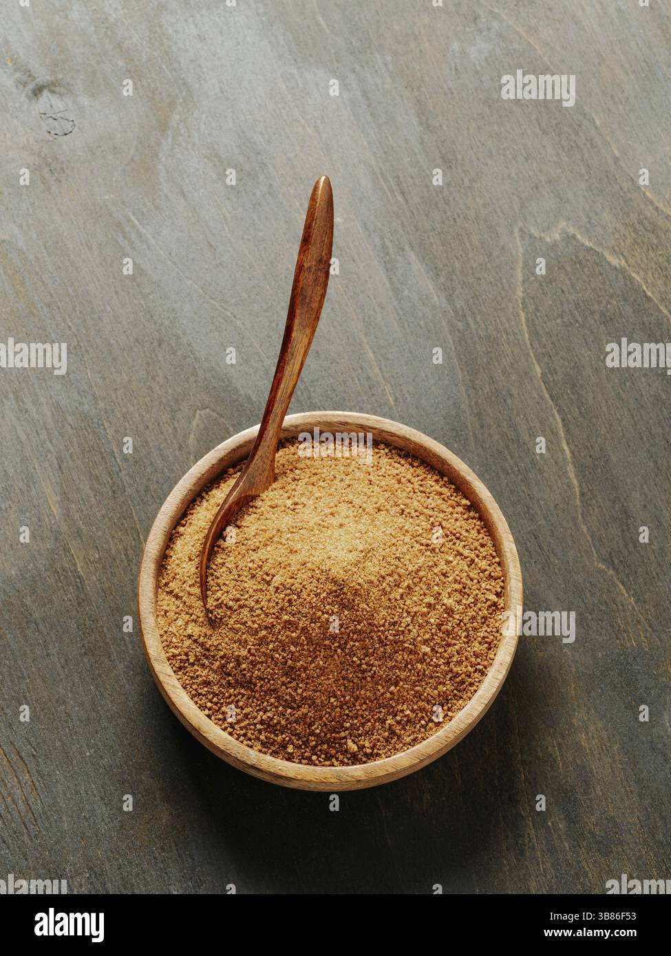 Bowl and spoon of coconut brown sugar on wooden background.Top view of ...