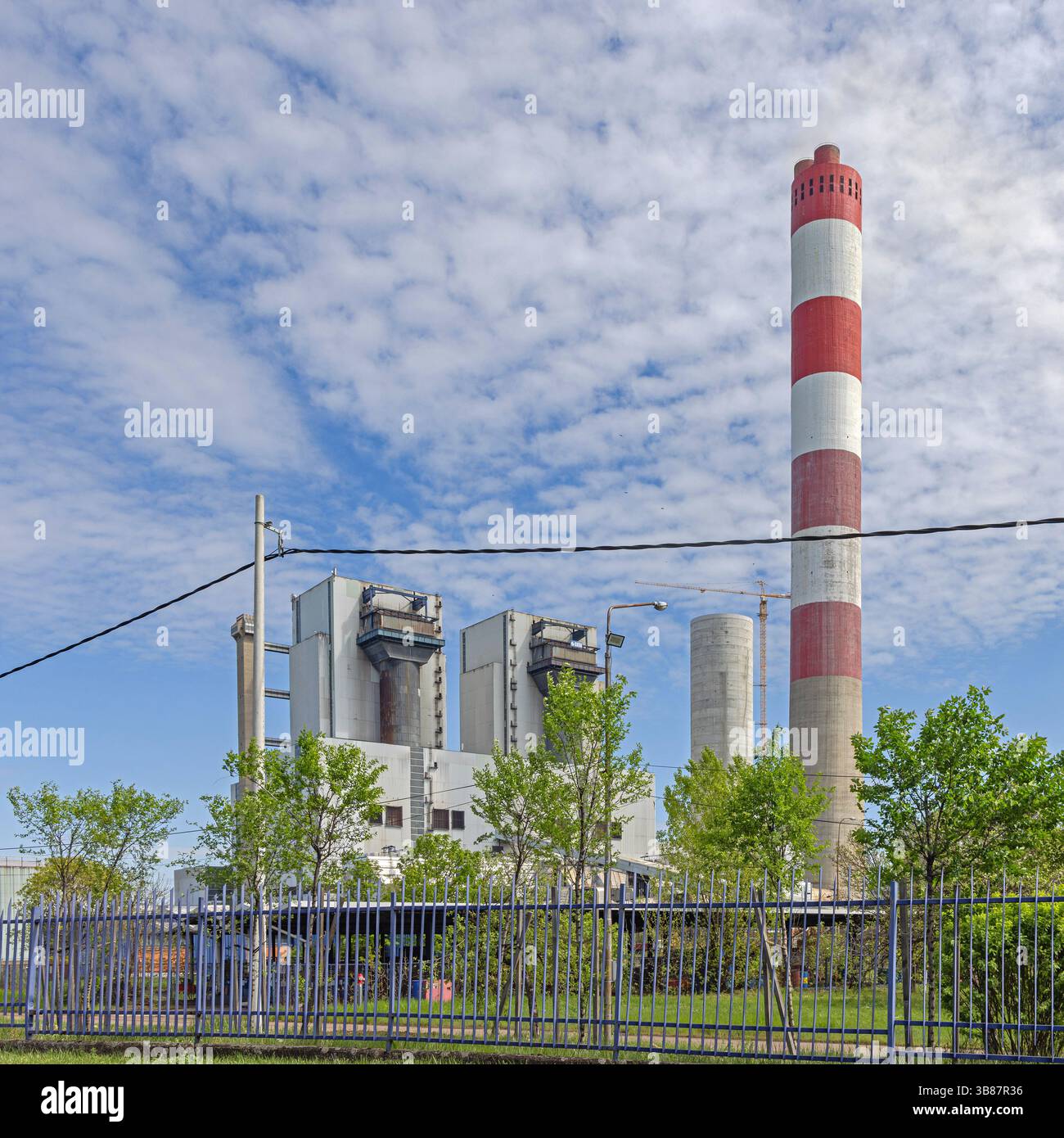 Obrenovac, Serbia - April 04, 2024: Red and White Chimney at Thermal Power Plant Facility Spring Day Cloudy Sky. Stock Photo