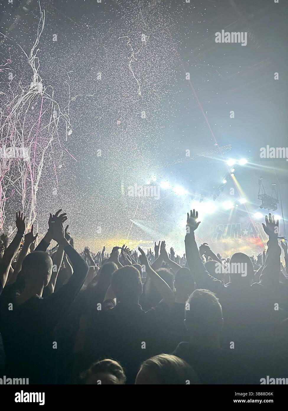 Fans cheer under stage lights and red streamers at Sum 41 concert, Co-op Live Arena, Manchester, 28 October 2024. Band not visible. - Smartphone Captured Stock Image
