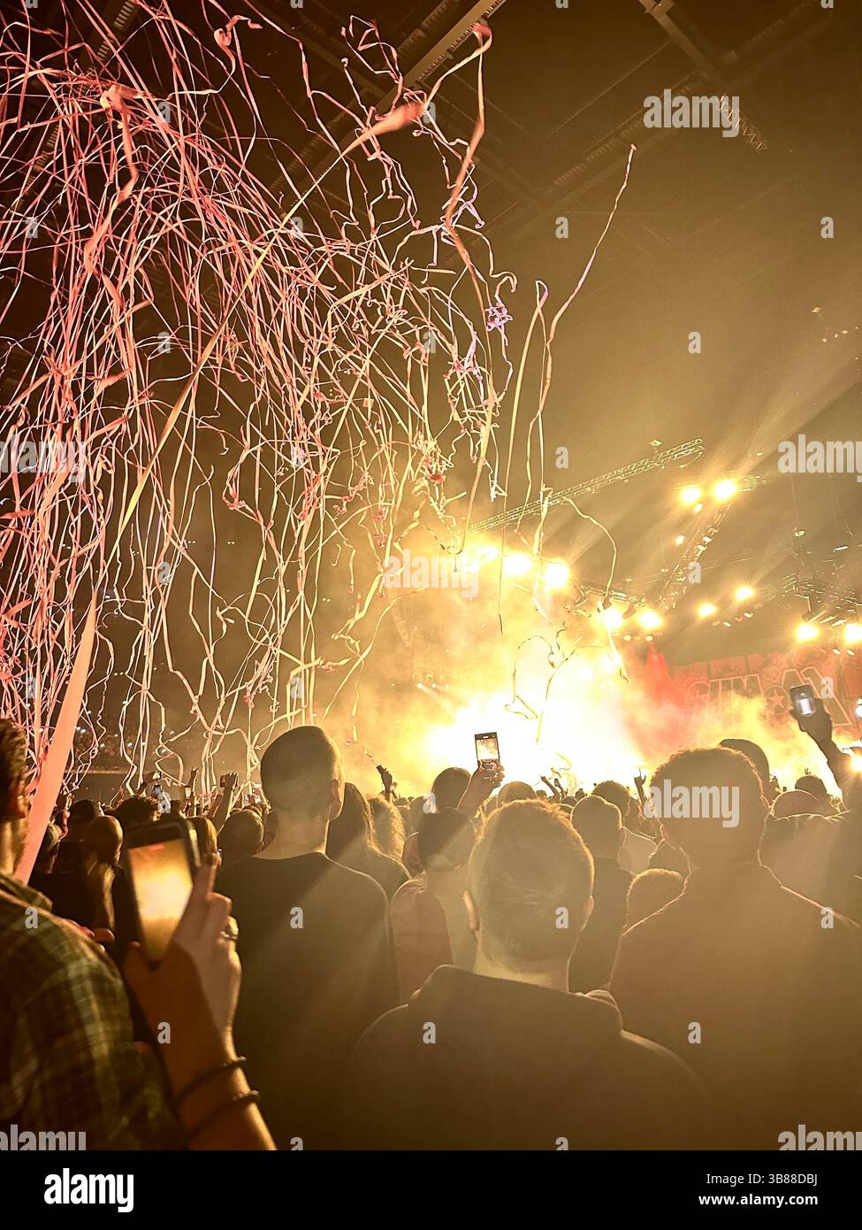 Fans cheer under stage lights and red streamers at Sum 41 concert, Co-op Live Arena, Manchester, 28 October 2024. Band not visible. - Smartphone Captured Stock Image