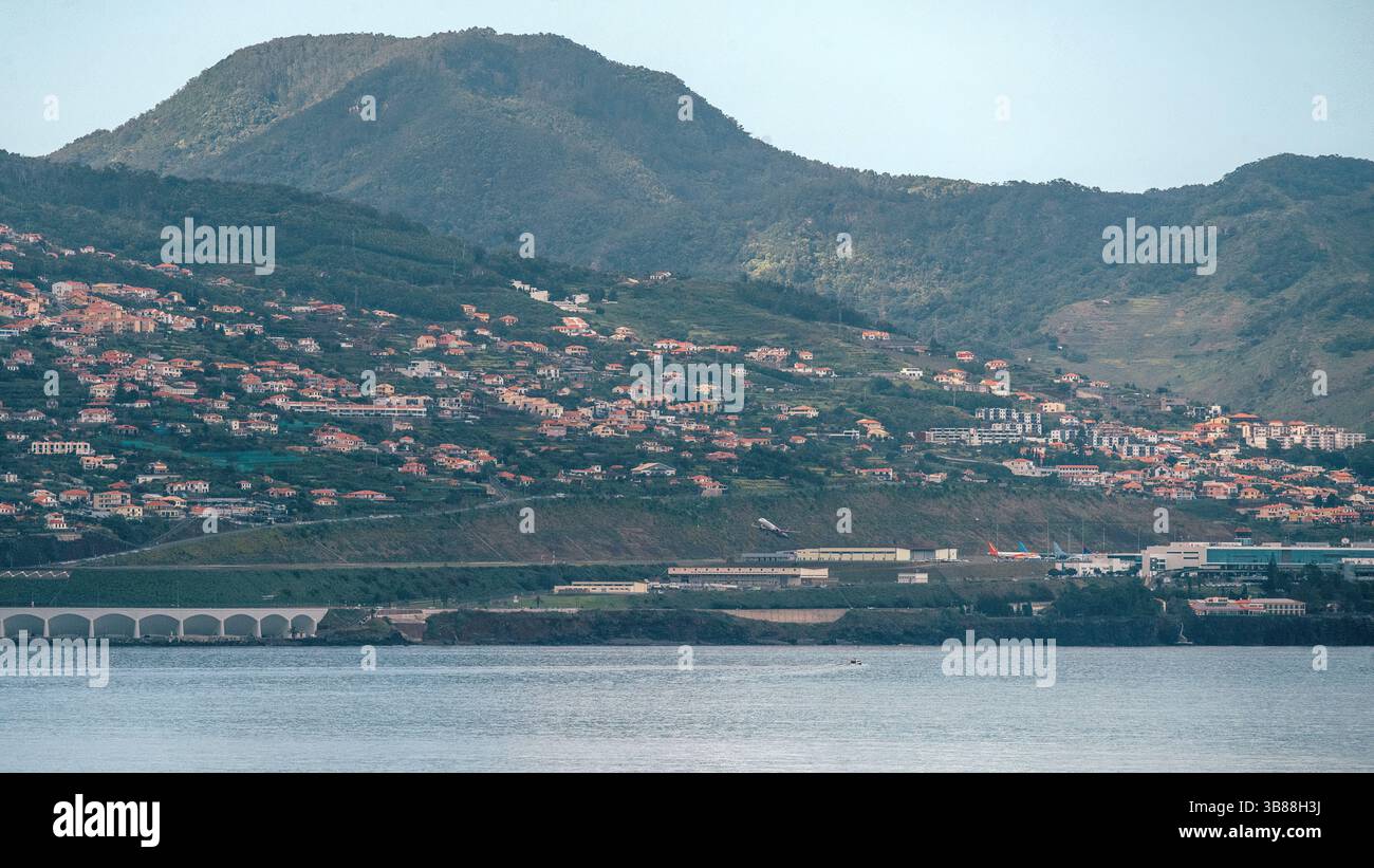 Madeira Funchal Airport (FNC) is known for its challenging runway. One end is built on concrete pillars with nearby steeply climbing terrain Stock Photo