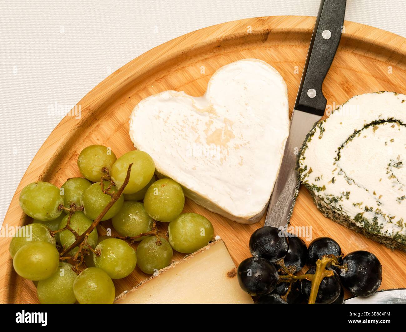 Wedding cheese platter with grapes and a heart-shaped cheese centerpiece, perfect for a romantic and gourmet celebration. Stock Photo
