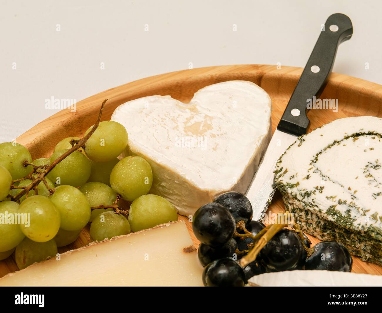 Wedding cheese platter with grapes and a heart-shaped cheese centerpiece, perfect for a romantic and gourmet celebration. Stock Photo