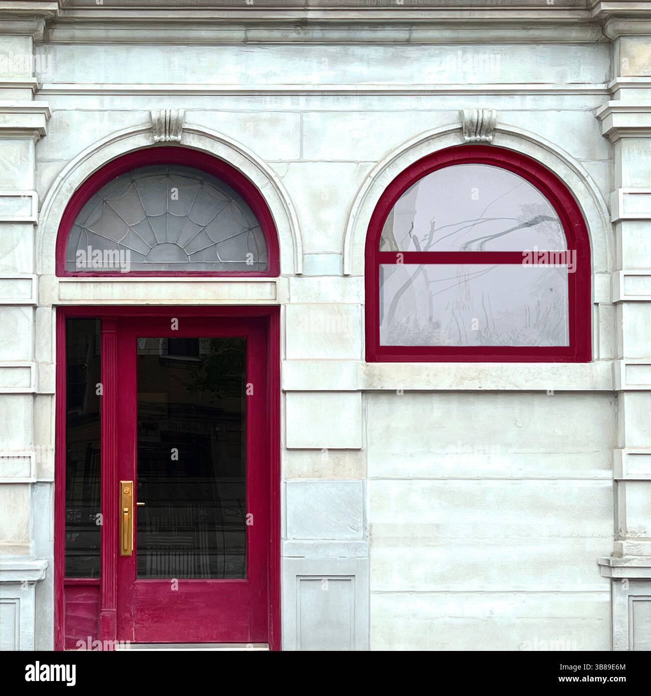 Aarched doorway with a deep red frame and matching arched window set in a pale stone neoclassical Chicago facade - Smartphone Captured Stock Image