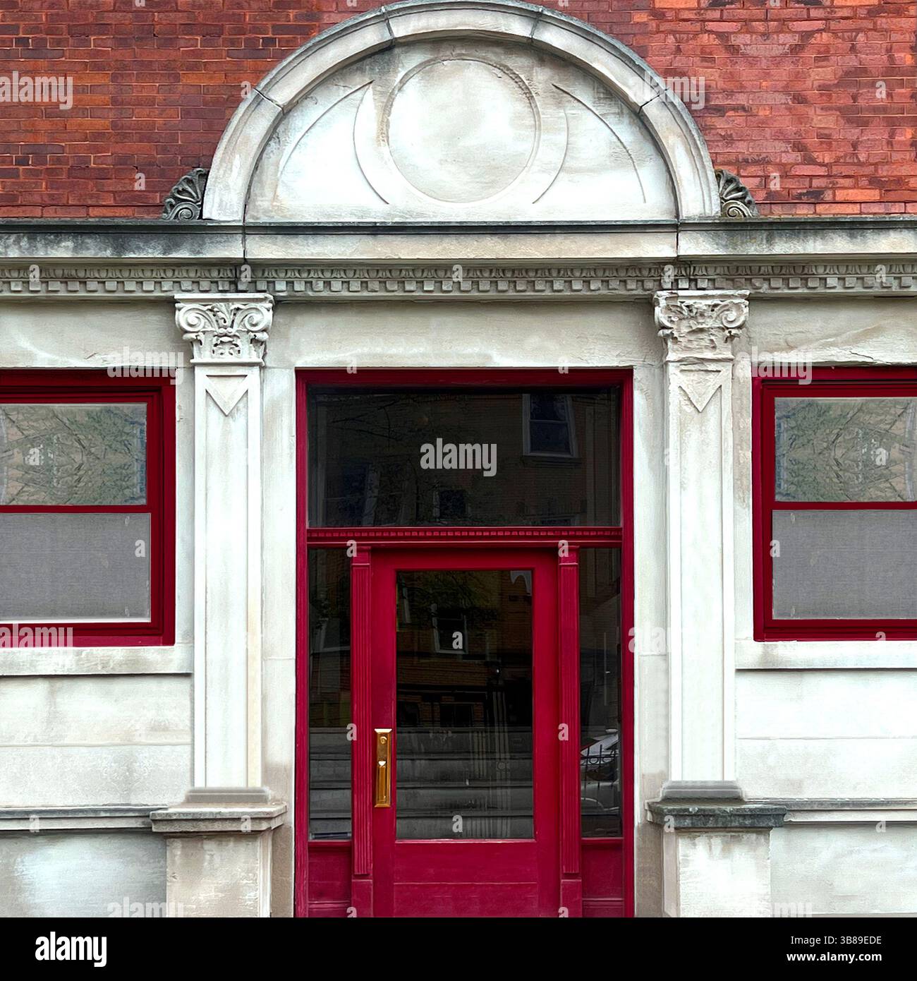 Bold red doorway framed by classical architectural detailing with Corinthian pilasters and a rounded pediment on a Chicago stone facade - Smartphone Captured Stock Image